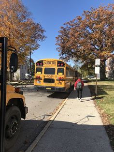 a school bus parked on the side of a road next to a tree filled street