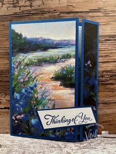 a greeting card with an image of a river and flowers on it, which reads thinking of you