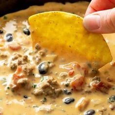 a hand dipping a tortilla chip into a bowl of quesadilla soup