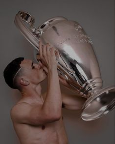 a shirtless man holding up a silver trophy in front of his face and chest