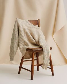 a chair with a blanket on top of it next to a white cloth draped over the back