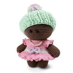 a crocheted teddy bear wearing a pink dress and green knitted beanie