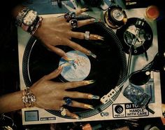 several hands on top of a record player surrounded by jewelry and other items that include rings