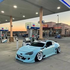 a blue car parked in front of a gas station