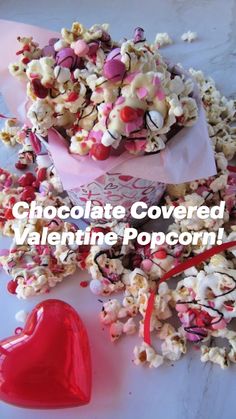 a bowl filled with candy and popcorn next to a heart shaped object on a table