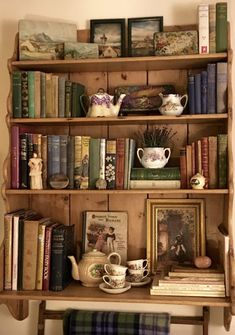 an old wooden shelf with books and tea cups on it, along with other antique items