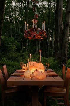 a table with candles and plates on it in the middle of a forest at night