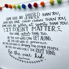 a white board with writing on it and pom - poms hanging from the wall