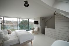 a bedroom with white walls and flooring next to a large window overlooking the water