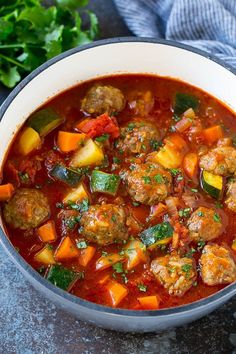 a bowl filled with meatballs and vegetables next to some parsley on the side