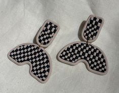 two black and white checkered earrings on a white cloth