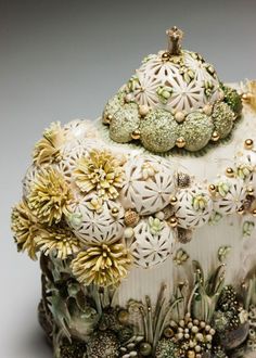 an elaborately decorated cake with flowers on it's sides and gold trimmings