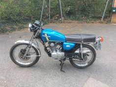 a blue motorcycle parked in front of a fence