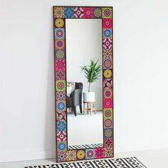 a mirror sitting on top of a white floor next to a potted green plant