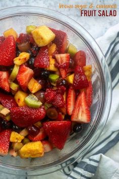 a glass bowl filled with fruit salad on top of a white and black striped towel