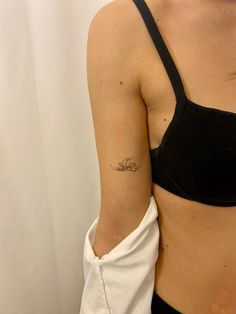 a woman with a small tattoo on her left arm, wearing a black bra top