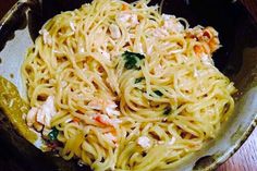 a bowl filled with pasta and chicken on top of a wooden table