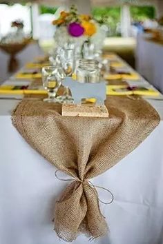 the table is decorated with burlap and silverware for guests to eat at