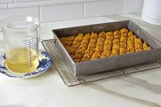 a pan filled with pastries next to a cup of tea on a counter top