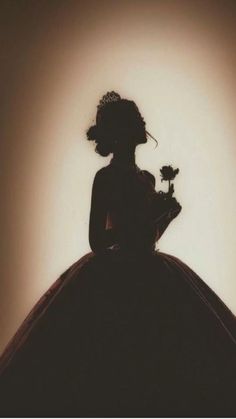 the silhouette of a woman in a dress holding a flower