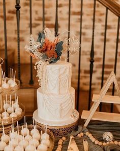 a white wedding cake and desserts on a table in front of some wooden stairs