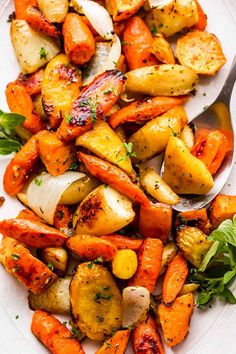 roasted carrots and potatoes with herbs on a white plate