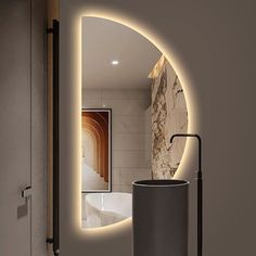 a bathroom with a round mirror and light on the wall, along with a trash can