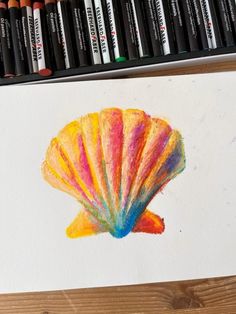 a drawing of a shell with colored pencils next to it