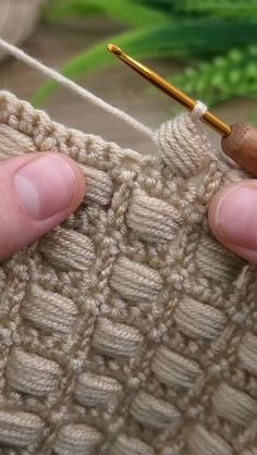 someone is knitting with a needle on the end of a knitted piece of cloth