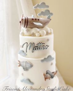 a three tiered cake decorated with airplanes and clouds