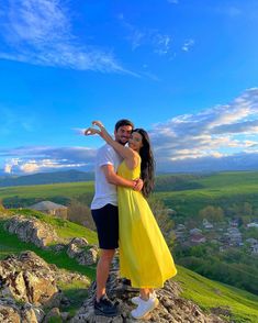 a man and woman standing on top of a rock with their arms around each other