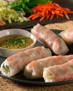 some food is sitting on a black plate and next to a bowl of dipping sauce