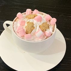 a cup filled with marshmallows and cookies on top of a white plate