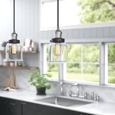 three lights hanging from a kitchen ceiling over a sink and counter top with windows in the background