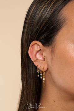 a close up of a woman's ear wearing gold and green earrings with dangling beads