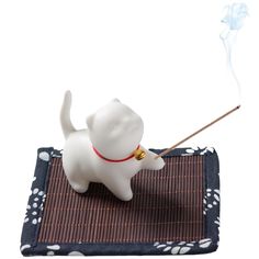 a small white dog with a stick in it's mouth on top of a mat