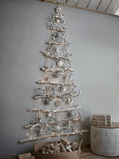 a christmas tree made out of branches and ornaments in a room with a basket on the floor