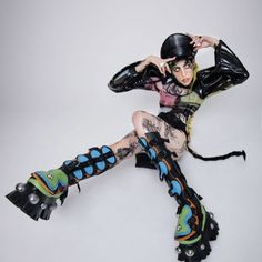 a woman with black hair and tattoos sitting on the ground wearing roller skates while holding her hands behind her head