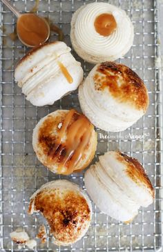 four different types of pastries on a cooling rack with peanut butter and caramel sauce