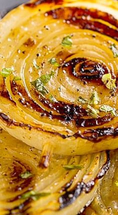 grilled onions on a plate with herbs and seasoning sprinkled around them