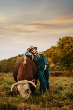 a woman standing next to a cow in a field