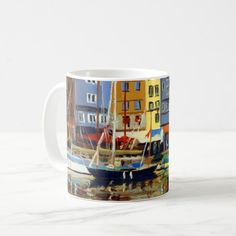 a coffee mug with boats on the water in front of some colorful buildings and blue sky