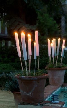 lit candles are placed in clay pots next to a pool