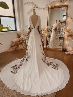 a wedding dress on display in front of a mirror with flowers and vines all over it