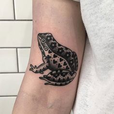 a black and white frog tattoo on the arm