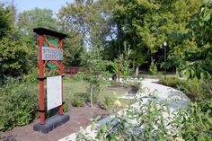 a sign in the middle of a park with trees and bushes around it that reads, community garden