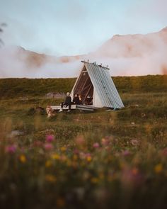 two people sitting in a teepee with their dog on the ground next to it