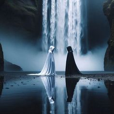 two women standing in front of a waterfall with their backs turned to the camera, facing each other