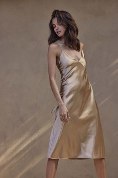 The Silky Satin Midi is the slip dress of your dreams. Featuring a seamed bust and v-neckline that references vintage silk slip styling, seamlessly contrasted against a modern midi length. The satin shoulder straps cross at the back, lending a sophisticated accent to its simplicity. Paying homage to the mesmerising glow of Marrakesh, this golden hue embodies gilded glamourWhilst we aim to ensure that every image accurately depicts the true colour, please consider that our colours can vary slight Gold Dress Wedding Guest, Gold Dress Wedding, Bridesmaid Dresses Gold, Gold Bridesmaid Dress, Gold Slip Dress, Wedding Gown Trends, Nude Slip Dress, Gold Bridesmaid Dresses, Designer Bridesmaid Dresses