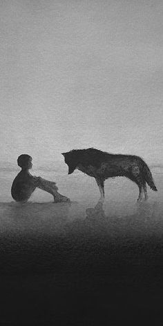 a man sitting on the ground next to a wolf